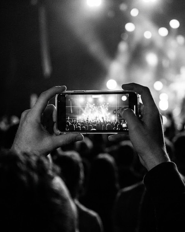 A phone filming a stage from the crowd